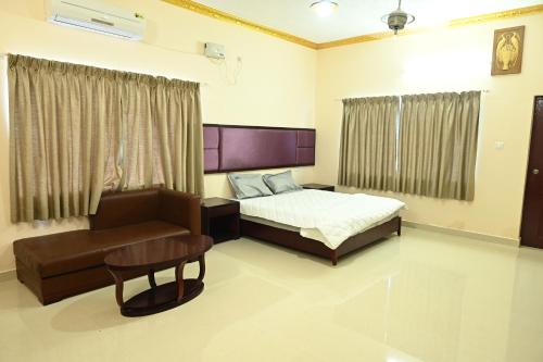 Un dormitorio con una cama, una silla y un sofá. en Athithi Resorts, en Yelagiri