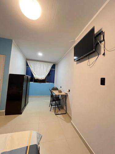 Habitación con mesa y TV en la pared. en Condominio Confortable, en Talara