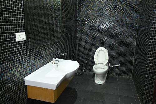 Un baño con inodoro, lavabo y espejo. en Athithi Resorts, en Yelagiri
