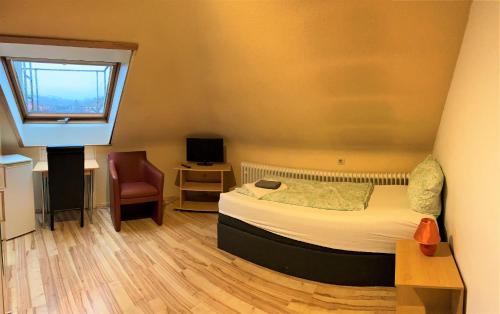 a bedroom with a bed and a window and a chair at Penthouse - 4-Zimmer und Terrasse in Karlsbad