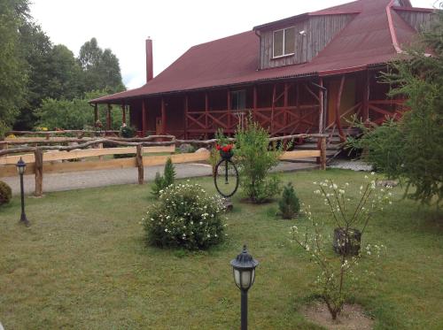 a large red barn with a house in the background at Globepark in Mažonai
