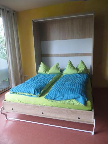 a bed with blue and green pillows on it at Gartenhaus Klotzsche in Dresden