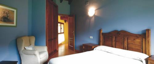 een slaapkamer met een bed, een stoel en een raam bij El Crucial in Cangas de Onís