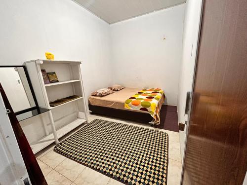 ein kleines Zimmer mit einem Bett und einem Regal in der Unterkunft RUMAH 25 SYARIAH in Bukittinggi