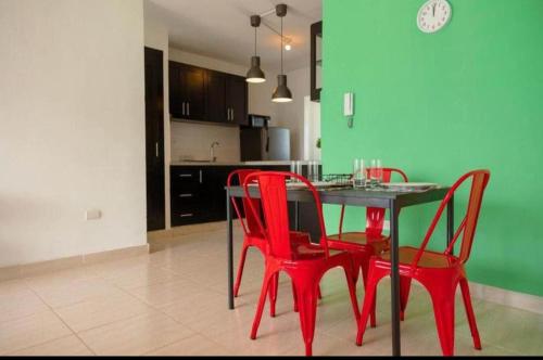 ein Esszimmer mit roten Stühlen, einem Tisch und einer Küche in der Unterkunft corona plaza in Santiago de los Caballeros