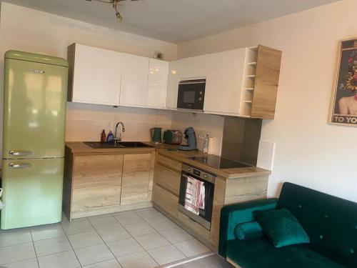 une cuisine avec des armoires blanches et un réfrigérateur vert dans l'établissement Paris/Stade de France, parking sous-sol, à Aubervilliers