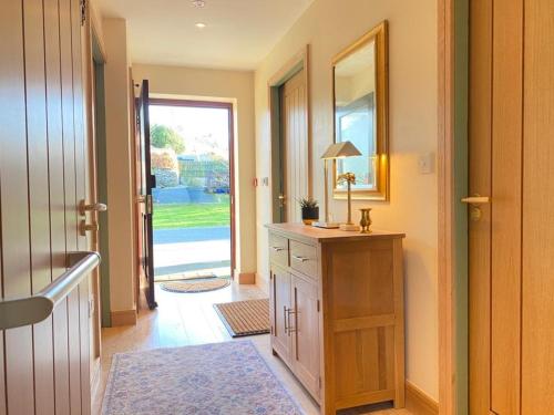 a hallway with a dresser and a door with a mirror at Lake District romantic get away in 1 acre gardens off M6 in Penrith