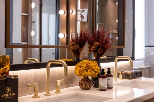 a bathroom sink with two faucets and flowers on it at Umiltà 36 in Rome