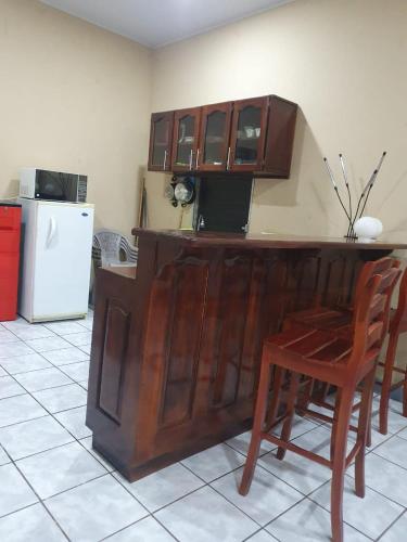 een keuken met een houten aanrecht met een stoel en een koelkast bij Ixoras Guest House in Moyogalpa