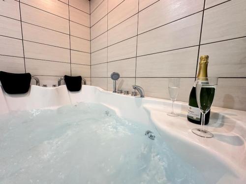 a bath tub with a champagne bottle and wine glasses at E Servagnat T3 luxe avec Sauna Jacuzzi et Hammam in Épernay