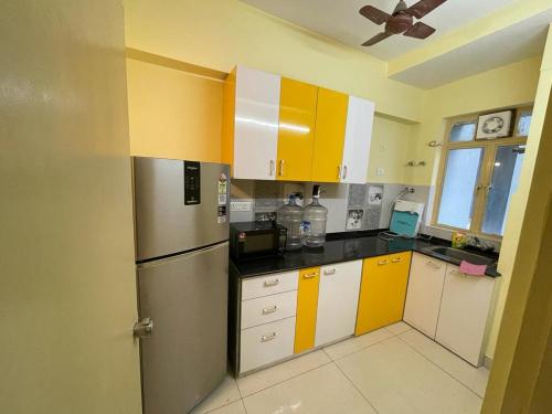 a kitchen with yellow and white cabinets and a refrigerator at Merlin Legacy in Kolkata