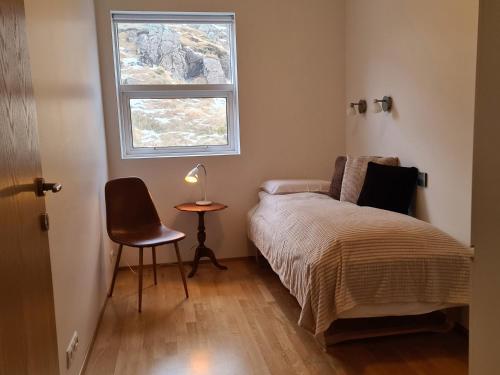 1 dormitorio con 1 cama, 1 silla y 1 ventana en Geithellar, en Djúpivogur