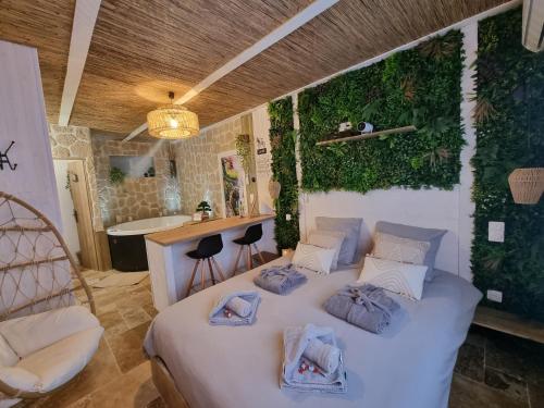 a bedroom with a white bed with plants on the wall at Les Spas de la mer, Suite & Spa, Love room, Plein Cœur du Grau in Le Grau-du-Roi