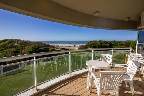 a balcony with white chairs and a table and the ocean at Marcin Hotel in Carilo