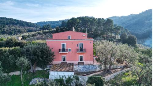 ein großes rosa Haus auf einem Hügel mit Bäumen in der Unterkunft I Frangiventi in Rodi Garganico