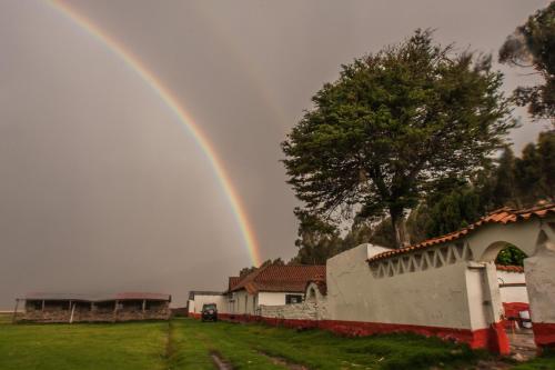 a rainbow is in the sky over a yard at Fundo Chincheros Lodge in Juliaca