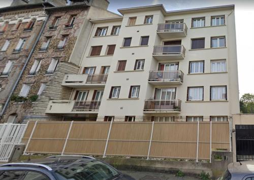 un grand bâtiment blanc avec une clôture devant lui dans l'établissement Très charmant appartement proche de Paris, à Aulnay-sous-Bois