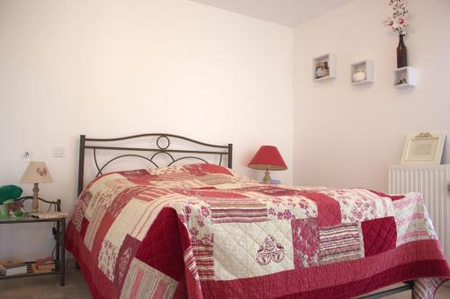 1 dormitorio con 1 cama con edredón rojo y blanco en A l'Orée du Bois, en Audenge