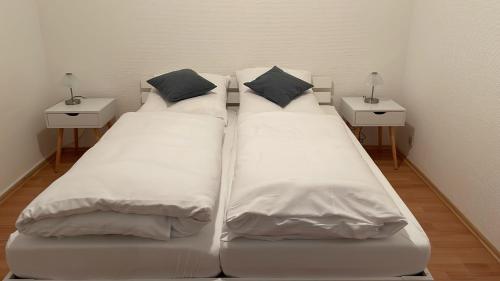 2 große weiße Betten in einem Zimmer mit 2 Tischen in der Unterkunft Ferienwohnung MeerLüst - Meerblick in Schillig