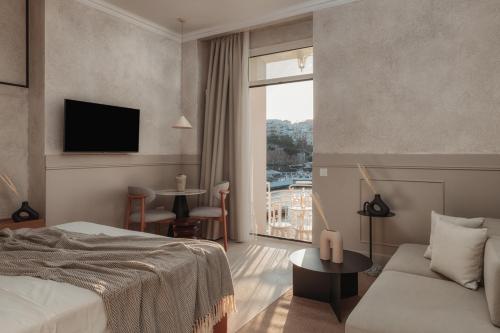 a hotel room with a bed and a couch and a window at Luxury Suites by Lato in Agios Nikolaos