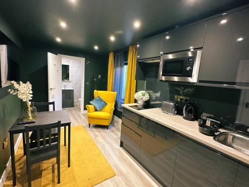 eine Küche mit einem Tisch und einem gelben Stuhl in der Unterkunft Sky City Apartments in Coventry