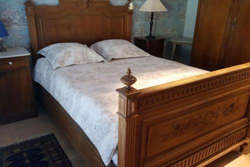 a large bed with a wooden frame in a bedroom at Appart. 3 chambres, jacuzzi en été, dans un jardin in Geneva