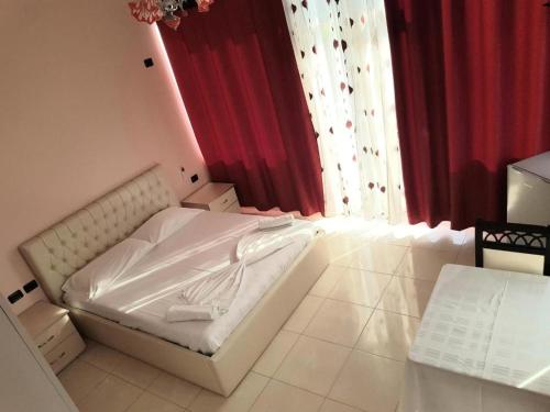 Cette chambre comprend un lit blanc et des rideaux rouges. dans l'établissement Fari Hotel, à Golem