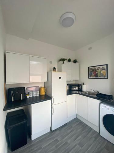 a kitchen with white cabinets and a refrigerator at Anfield city break in Liverpool