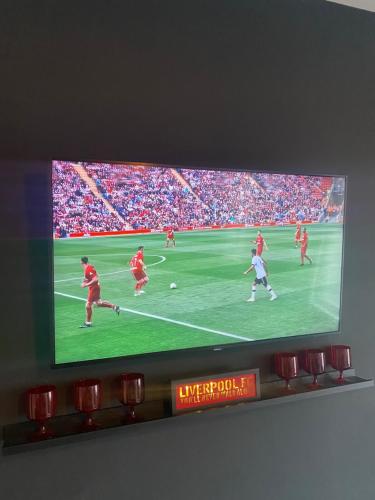 een flatscreen-tv met een voetbalspel erop bij Anfield city break in Liverpool