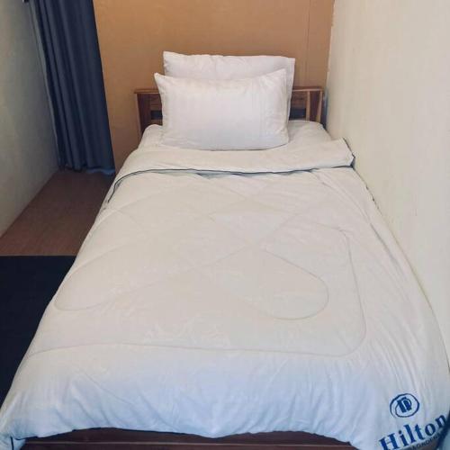 a bed with white sheets and pillows in a room at Chubby5 Room 7 in Bang O