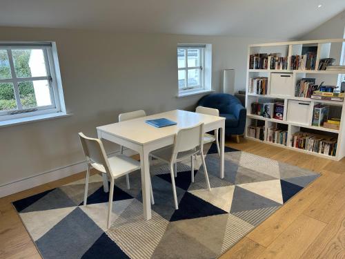 a table and chairs in a room with a book shelf at Immaculate Studio Apartment just outside Penzance in Penzance