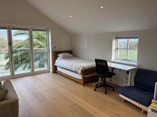 um quarto com uma cama, uma secretária e uma cadeira em Immaculate 1-Bed Apartment in Penzance em Penzance