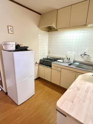 a kitchen with a white refrigerator and a stove at ᛃ 眠りの癒 ᛃ Cozy Stay In The Heart of Beppu Apt 202 in Beppu