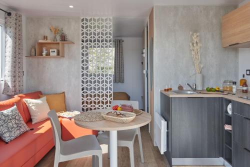 eine Küche und ein Wohnzimmer mit einem Tisch und einem Sofa in der Unterkunft Camping La Forêt Stella-Plage in Stella-Plage