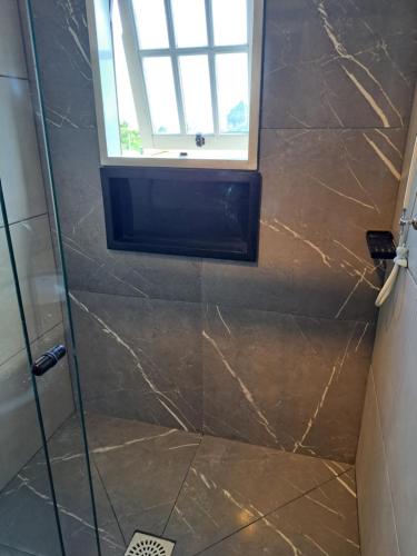 a shower with a glass door and a window at Sobrado com vista profissional do mar in Arroio do Sal
