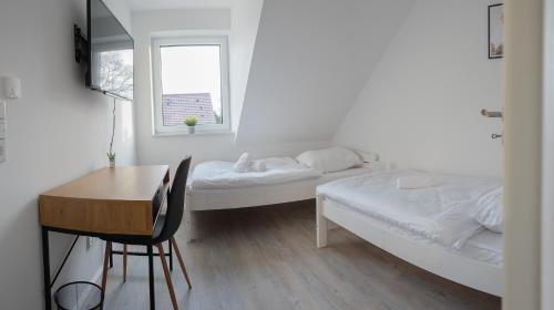 a bedroom with two beds and a desk and a window at Monteur- & Ferienoasen Ostfriesland in Rhauderfehn