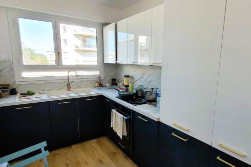 une cuisine avec des armoires noires et blanches et un évier dans l'établissement Riverside Retreat with balcony & parking, à Courbevoie