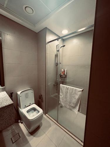 a bathroom with a toilet and a glass shower at R F Homes Shared Apartment in Dubai in Dubai