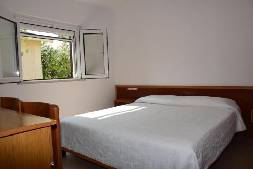a bedroom with a white bed and a window at Pellegrino Village in Vieste