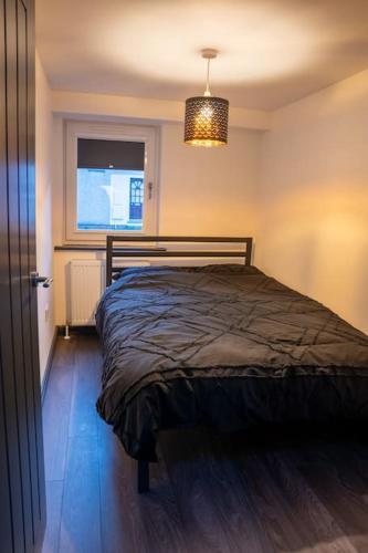 a bedroom with a bed and a window and a chandelier at The Porty Beach House in Edinburgh