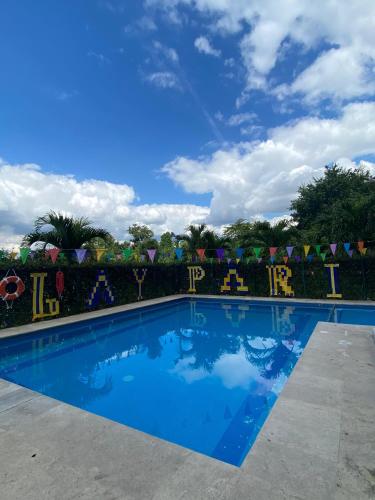 a swimming pool in front of a hedge with a blue sky at Paris FC Express in Poza Rica de Hidalgo