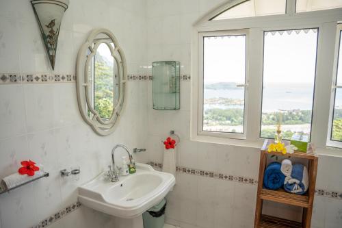 a white bathroom with a sink and two windows at Beau Soleil Stunning Sea View One Bedroom Apartment in Mahe