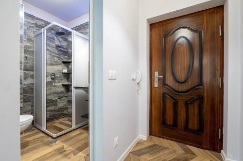 een badkamer met een houten deur en een toilet bij Azurro Residence in Sofia