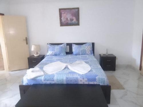 sypialnia z niebieskim łóżkiem i 2 ręcznikami w obiekcie RT GUEST HOUSE w Port-Gentil