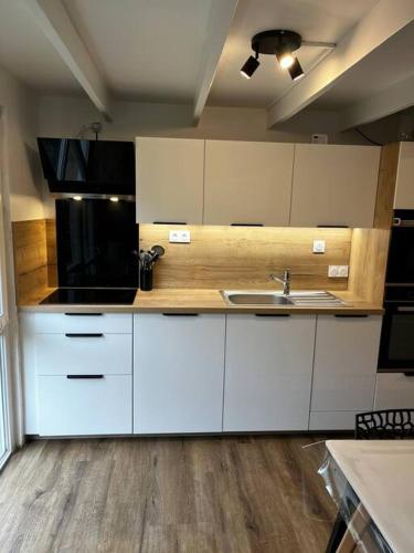 La cuisine est équipée de placards blancs et d'un four micro-ondes noir. dans l'établissement Gîte au bord du lac, à Royère-de-Vassivière