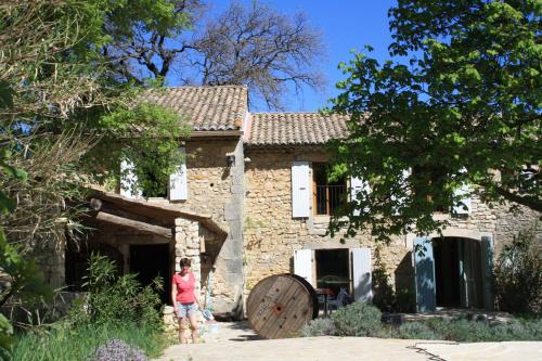 uma mulher em pé em frente a uma casa de pedra em La Crozette - Mas Provençal em Saint-Restitut