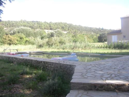 a pool of water in a yard with a stone wall at La Crozette - Mas Provençal in Saint-Restitut