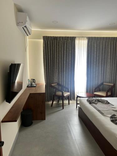 a hotel room with a bed and a desk with a television at Vrishi Inn in Bangalore