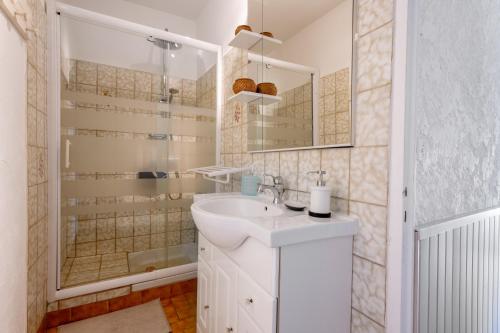 y baño blanco con lavabo y ducha. en Gite Les Aiguillans, en Mérindol-les-Oliviers