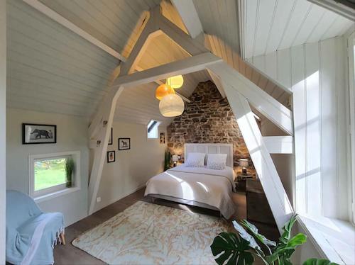 une chambre avec un lit et un mur en pierre dans l'établissement Les Tortues, maison bord de mer, plage à 200 m, à Plougasnou